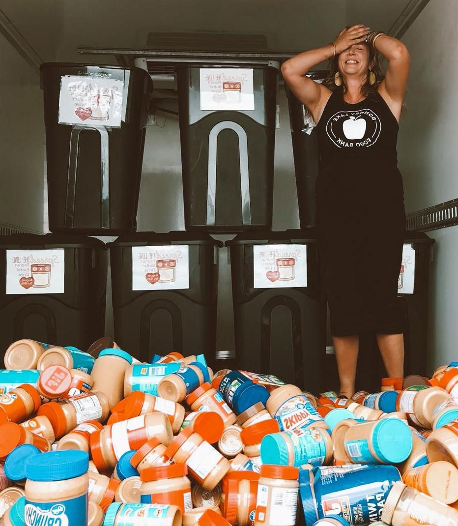 CEO Stacey Crnich stands in a truck laughing at the pile of peanut butter jars at her feet. 